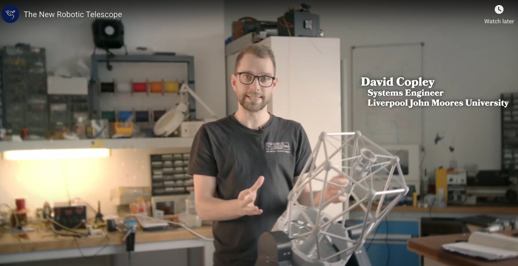 Still from NRT video showing Dave Copley talking about the telescope in the labs with a 3D print model of the NRT